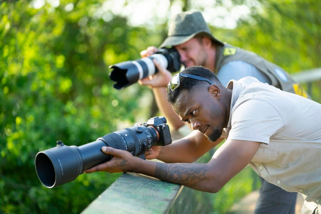 To mænd fotograferer med store objektiver i junglen.