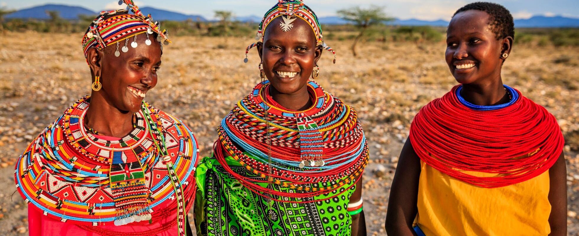 3 kvinder i Kenya iført traditionelle farverige dragter