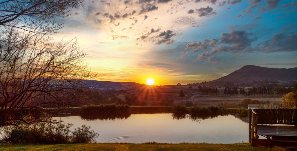 Solnedgang over sø i Sydafrika. Bjerge i baggrunden.