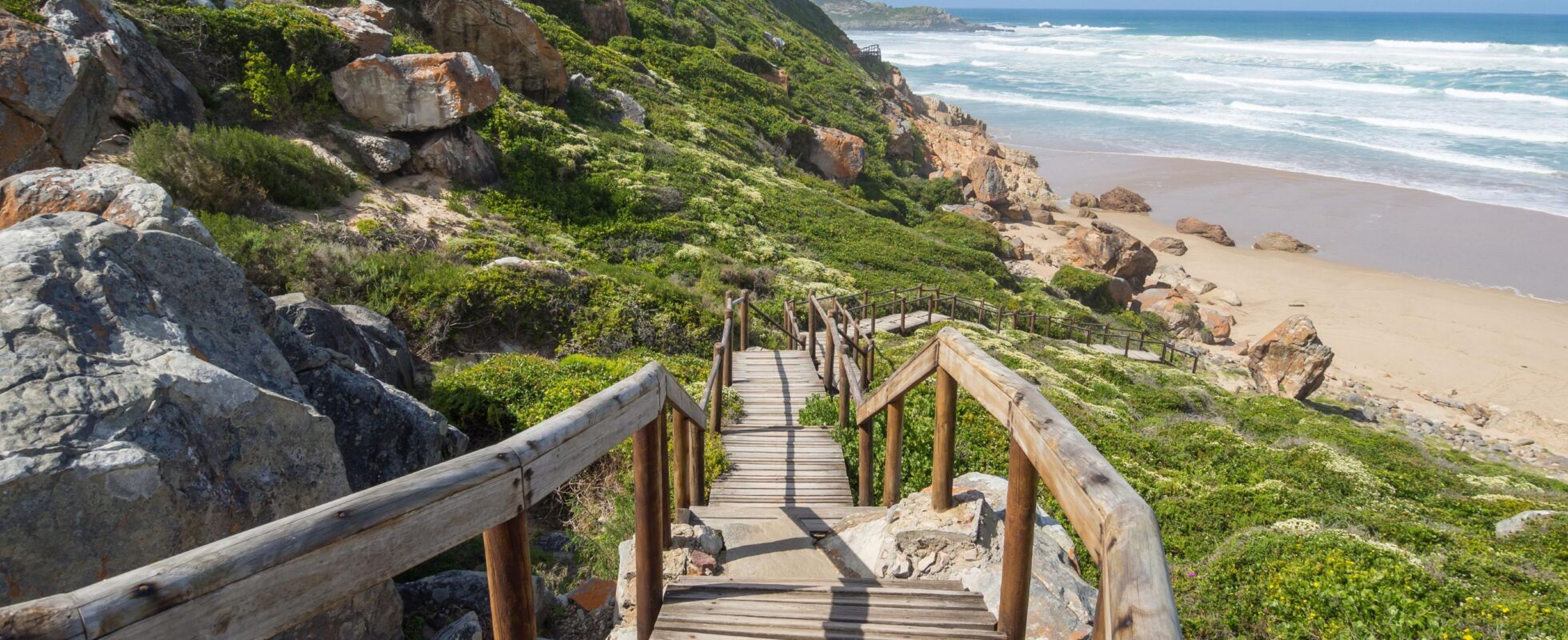 Trætrappe, der løber ned ad klipperne til kysten og havet