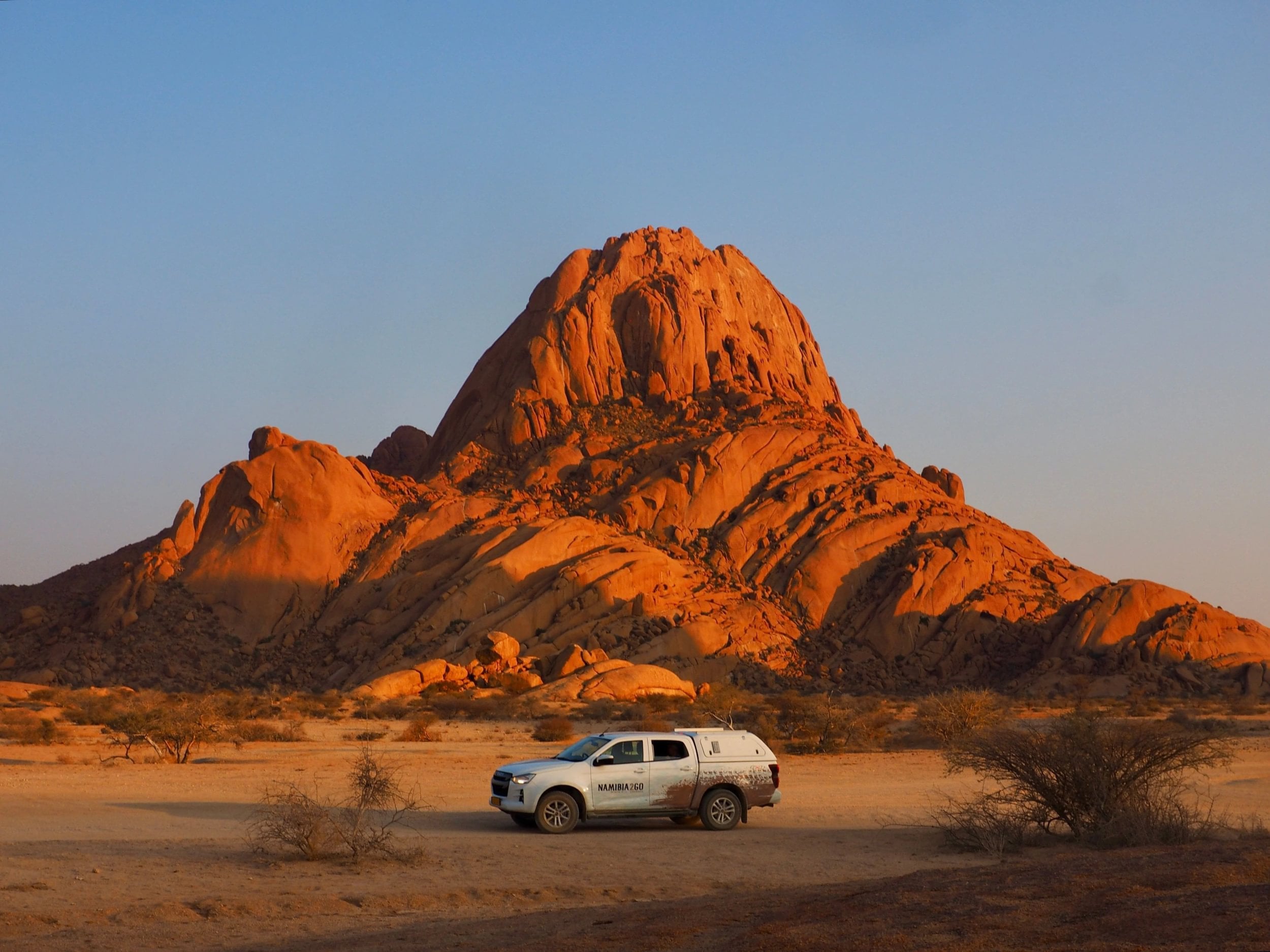 Safari-jeep står parkeret ved foden af Spitzkoppe ved solnedgang